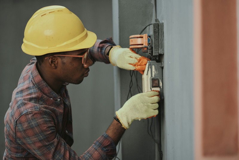 BANEC electrician wiring a wall-mounted distribution unit on site.