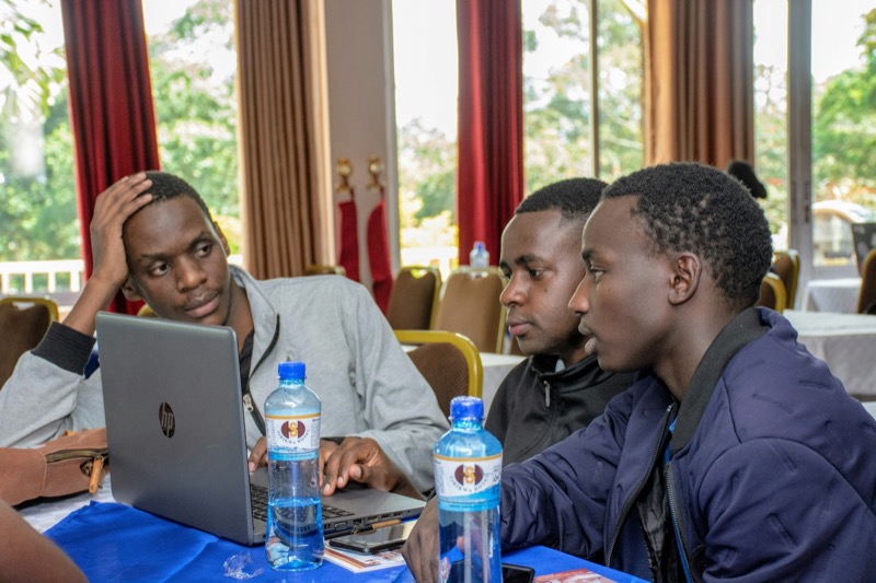 Three young engineers training together on laptops.