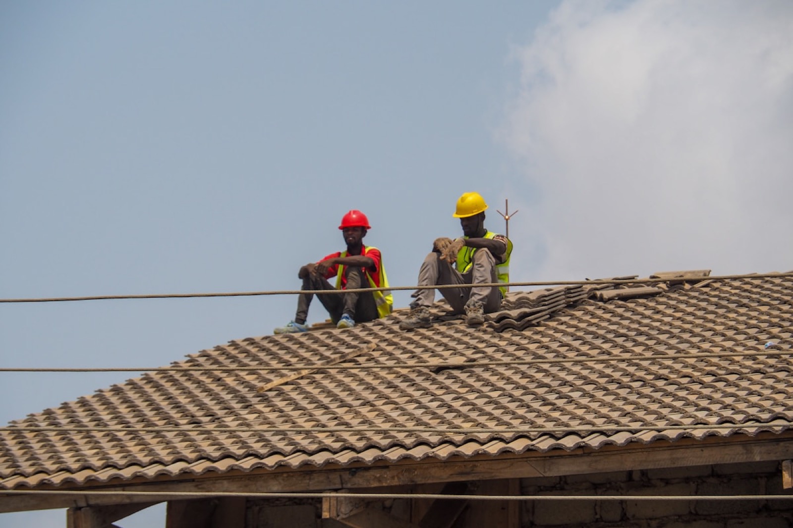 Two BANEC workers in helmets and high-visibility vests on a roof.